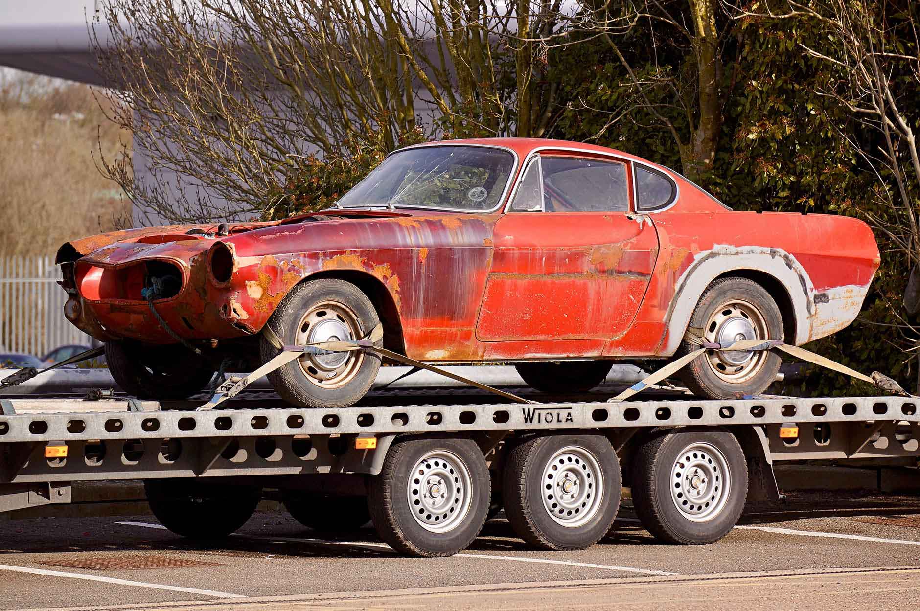 A red broken car on a Ftalbed Trailer 